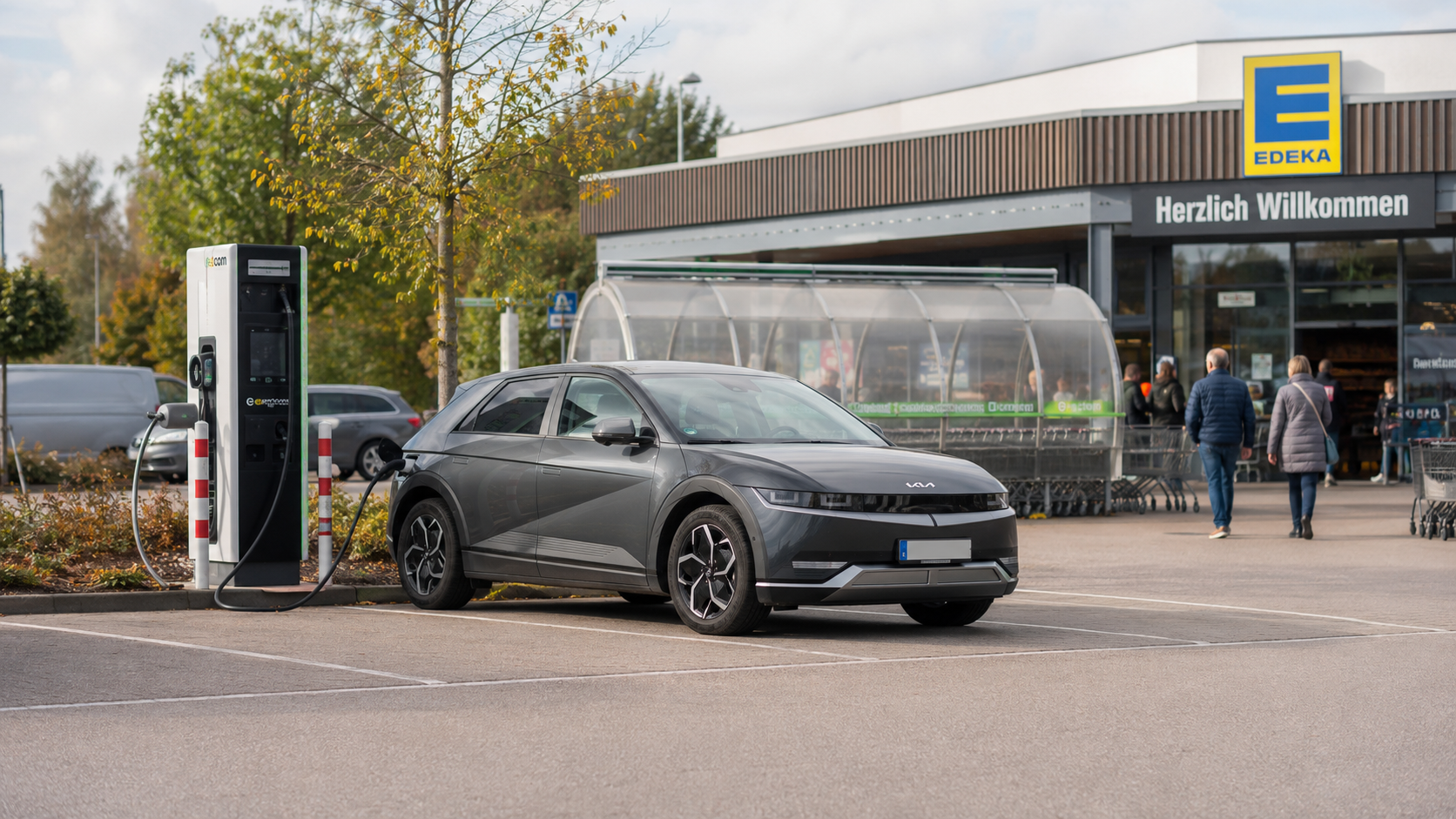 E-Auto l&auml;dt an einer AC-Lades&auml;ule auf einem Supermarkt-Parkplatz &ndash; g&uuml;nstig laden beim Einkaufen